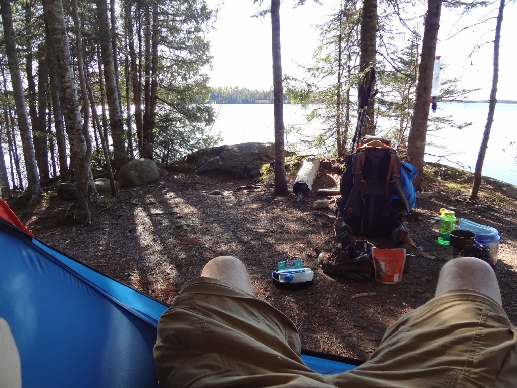 photo looking out at Lane Cove from a camp site on the shore. The author's crotch is in the foreground, various camping gear is in the middle ground.
