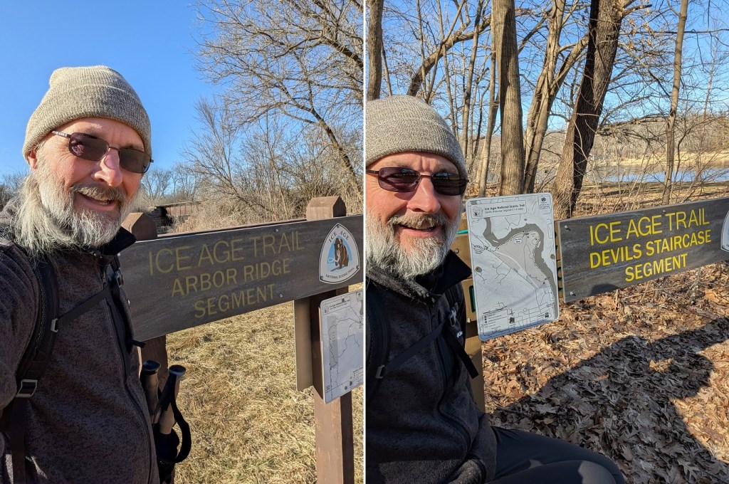 a bearded man in a gray beanie cap and a dark jacket poses in front of a trailhead sign for the Ice Age Trail